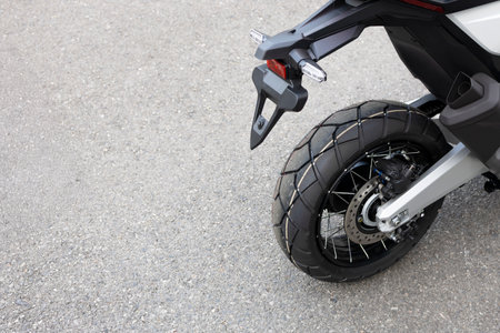 Rear wheel and disc brake of an adventure motorcycle parked on asphalt road in Thailand, captured in high detail.の写真素材