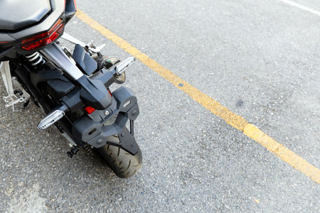 Rear wheel and disc brake of an adventure motorcycle parked on asphalt road in Thailand, captured in...