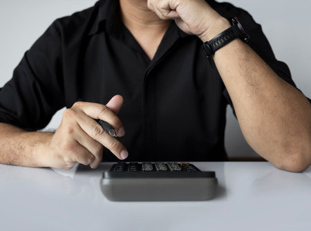 Businessman holding calculator and pen in front of keyboard, concept for finance, accounting, tax...