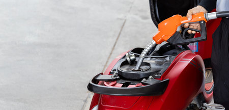 Hand refueling motorcycle at gas station, with gasohol 95 and gasohol 91 price indicators. Gasohol 95 price shown increasing with red arrow.の写真素材