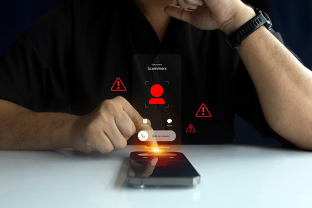 A man receives a scam call on his smartphone with warning icons, symbolizing cybercrime, phishing,...