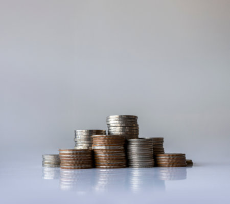 Piles of assorted coins arranged on white background symbolizing money, finance, saving, and...