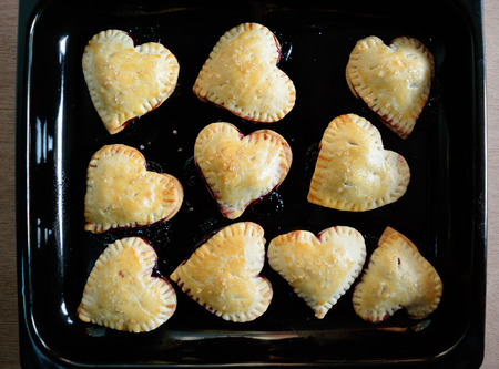 Fresh baked homemade raspberries and lemon pies crust hearts on a trayの写真素材