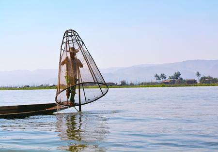 INLE LAKE, MYANMAR â JANUARY 21, 2017: Burmese Fisherman catching fish by a handmade net in Inle Lake, Myanmar.のeditorial素材