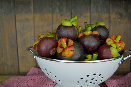 Fresh Mangosteen in a white bowl on wood backgroundの写真素材