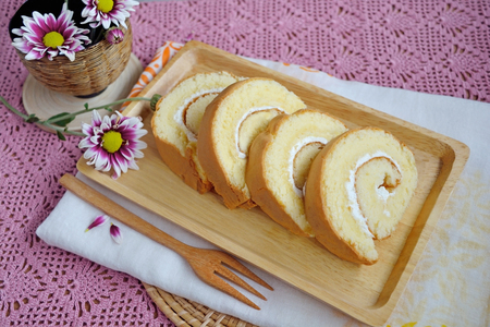 Pieces homemade vanilla cake roll on a wood plateの写真素材
