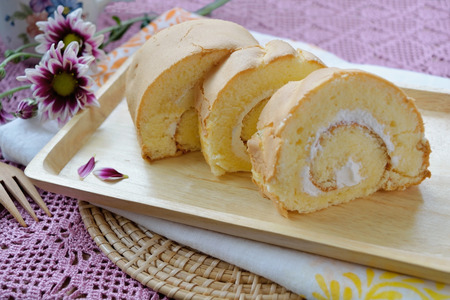 Pieces homemade vanilla cake roll on a wood plateの写真素材