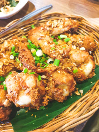 fried chicken with fried garlic and spring onions on topped served in a basketの写真素材