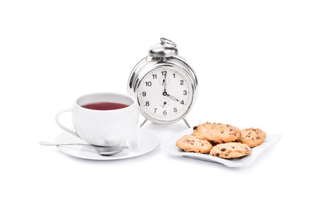 Cup of tea with chocolate chip cookies and a clock isolated on white backgroundの写真素材