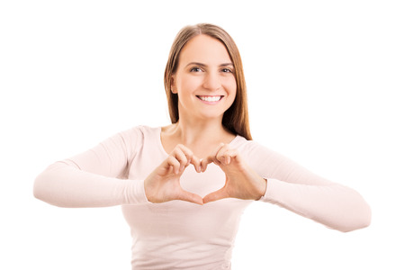 Beauty portrait of a young girl making a heart shaped hand gesture, isolated on white backgroundの写真素材