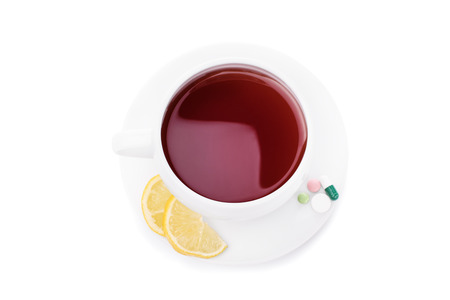 Cup of tea with slices of lemon and some pills isolated on white backgroundの写真素材