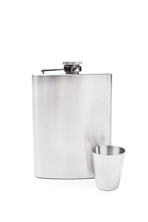 Metallic flask with a small glass placed next to each other isolated on white backgroundの写真素材
