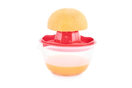 Half filled squeezer with an orange on it isolated on white backgroundの写真素材