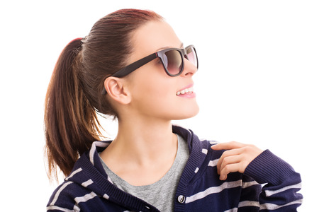 Hey you. Greeting with a smile. Young girl wearing sunglasses isolated on white backgroundの写真素材