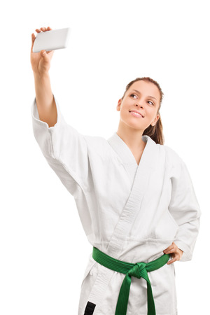 Sports and selfies. Young girl wearing kimono and making selfie isolated on white backgroundの写真素材