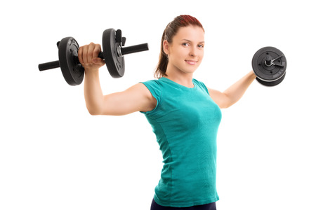 Hold them up! Young girl lifting dumbbells isolated on white background.の写真素材
