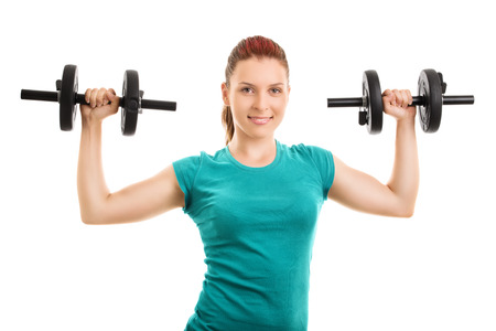Lift and hold. Young girl lifting up two dumbbells isolated on white backgroundの写真素材
