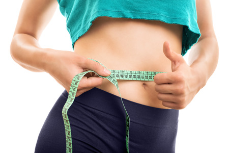Waistline. Young girl measuring her waist isolated on white backgroundの写真素材