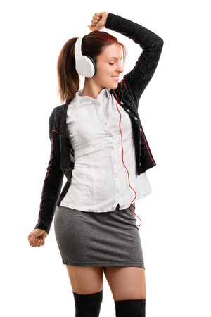 School girl in uniform listening music and dancing, isolated on white backgroundの写真素材