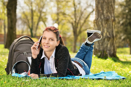 I'm down here enjoying spring time, you? Student in a park talking on the phone.の写真素材