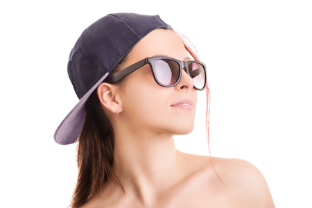 Beauty portrait of a young girl wearing sports hat and sunglasses isolated on white backgroundの写真素材