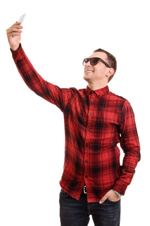 A portrait of a fashionable young man taking a selfie isolated on white background.の写真素材