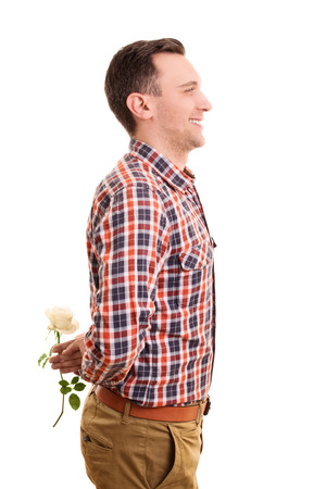 A portrait of a smiling young man hiding a flower isolated on white background.の写真素材