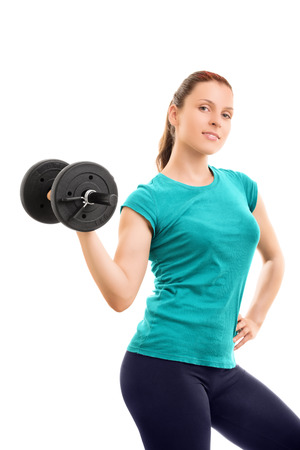 A portrait shot of a beautiful fit girl smiling and lifting a dumbbell, isolated on white background.の写真素材