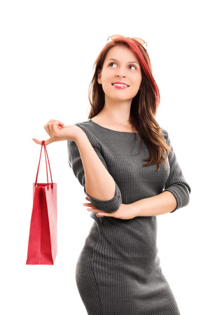 A portrait shot of a beautiful young girl in a dress, holding a shopping bag, isolated on white background.の写真素材