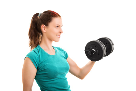 a portrait shot of a beautiful fit girl smiling and lifting a dumbbell, isolated on white background.の写真素材