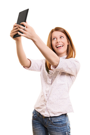 A portrait shot of a young beautiful girl taking a selfie with her tablet, isolated on white background.の写真素材