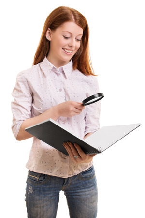 A portrait of a beautiful smiling female student, holding a magnifying glass and a book, isolated on white background.の写真素材