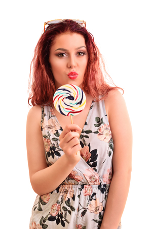 Portrait of a beautiful young girl holding a lollipop, sending a kiss, isolated on white background.の写真素材