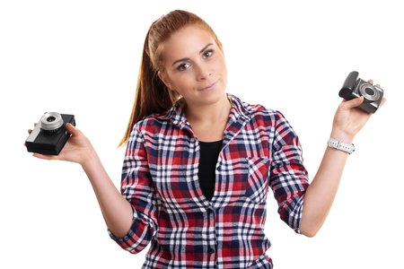 Young beautiful woman dressed in plaid shirt holding vintage and modern camera in each hand, isolated on a white background.の写真素材