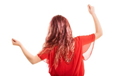Redheaded girl turned with her back, dancing, gesturing with arms up, isolated on a white backgroundの写真素材