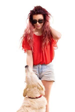 Beautiful young redhead girl with sunglasses, petting her dog preparing to go out for a walk, isolated on a white background.の写真素材