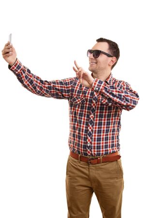 A portrait of a young fashionable man taking a selfie, isolated on white background.の写真素材