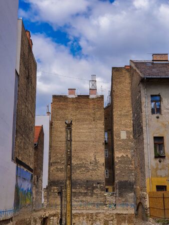 Empty construction site between old brick buildings against a blue sky. Construction of a building among the ruined neighboring buildings in Budapest. の写真素材