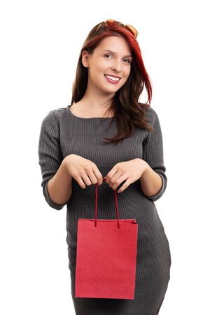 A portrait of a beautiful smiling young girl in a dress, holding a shopping bag, isolated on white background.の写真素材