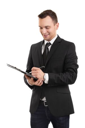 A portrait of a young businessman dressed in business casual clothes, writing on a clipboard, isolated on white background.の写真素材