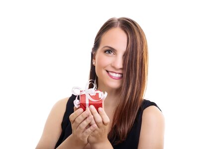 A portrait of a beautiful smiling young woman holding a wrapped gift, making an impression she's giving it to you, isolated on white background.の写真素材