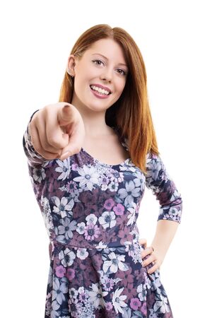 Beautiful fashionable young girl smiling and pointing a finger at you, isolated on white background.の写真素材