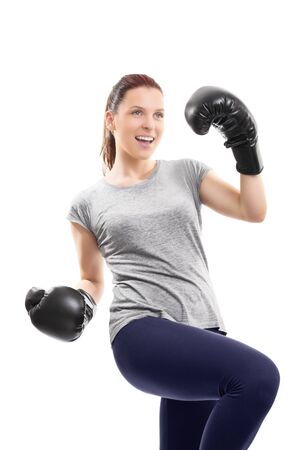 A portrait of a young beautiful girl with boxing gloves cheering and celebrating her success, isolated on white background.の写真素材