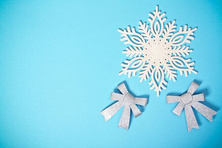 Christmas or winter composition. White snowflake with two glittery silver bows on pastel blue background. Christmas, winter, new year concept. Flat lay, top view, copy space.の写真素材