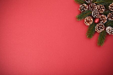 Christmas and New Year composition. Seasonal greeting card concept with pinecones and evergreen branches on red background. Christmas, winter, new year concept. Flat lay, top view, copy space.の写真素材