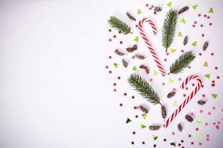 Christmas or New Year composition. Fir tree branches, candy cane, pinecones and confetti on white background. Christmas, winter, new year concept. Flat lay, top view, copy spaceの写真素材