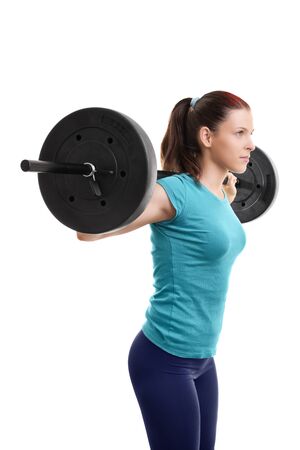 Beautiful fit young girl with barbell on her shoulders getting ready to do squats, isolated on white background.

の写真素材