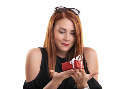 Portrait of a beautiful smiling girl holding a small wrapped gift box in both hands, isolated on white background. Christmas, New Year, Valentineâs gift concept.の写真素材