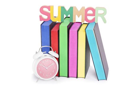 Summer, reading concept. Letters spelling SUMMER places over books with colorful sprayed edges and a clock, isolated on white background.の写真素材