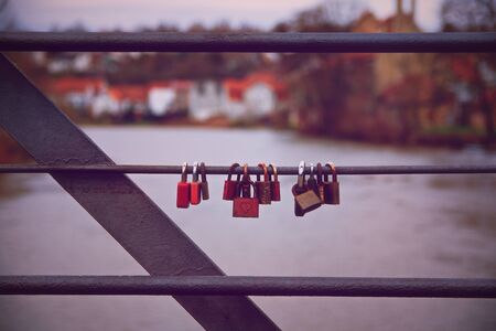 Lovelocks hanging on a bridge railing with a river in the background. Romantic lover padlocks on a...